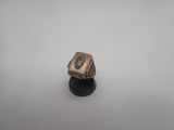 une bague en argent ornée d'une croix, posée sur un socle noir