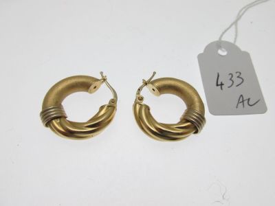 two pairs of gold hoop earrings on a white surface
