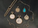 an assortment of antique pocket watches and necklaces on a black surface