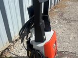 un pot de peinture orange et noir posé sur le trottoir, à côté d'un immeuble