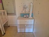 un lit de bébé à côté d'une commode dans une petite chambre