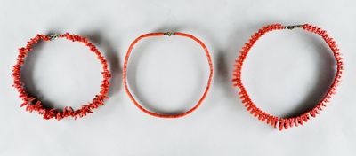 three red necklaces on a white surface