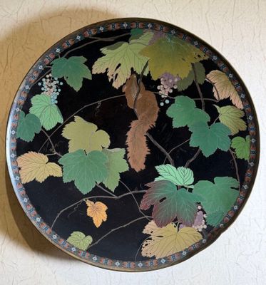 a decorative plate with leaves on it on a wall