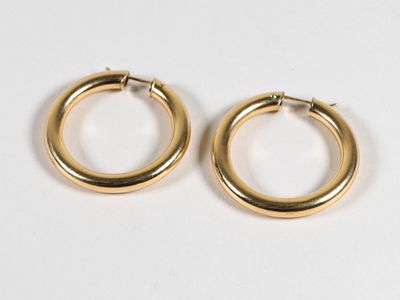 une paire de boucles d'oreilles en or sur fond blanc