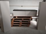 Plusieurs meubles sont empilés sur des palettes dans un entrepôt