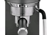 La machine à café est argentée et noire sur fond blanc.