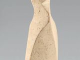 sculpture représentant une figure féminine sur un socle en pierre, sur fond gris