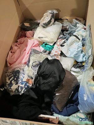 une boîte remplie de vêtements et un chat allongé par terre