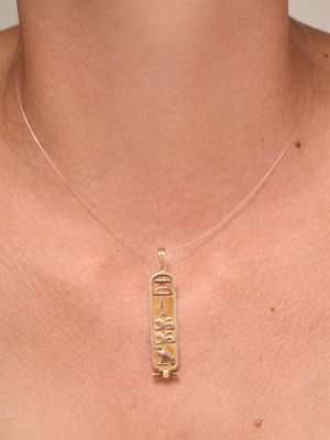 a close up of a woman wearing a gold necklace with an egyptian hierole on it