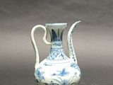 a blue and white vase with a handle on a table