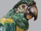 a figurine of a green and yellow parrot on a stand