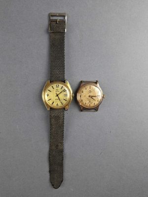 two watches are sitting next to each other on a gray surface