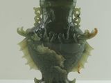 un vase vert orné d'un dragon, posé sur une table