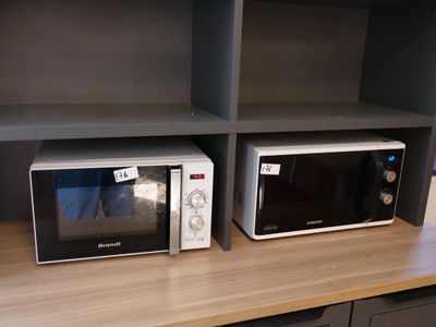 two microwaves sitting on a shelf in a kitchen
