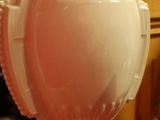 un vase blanc posé sur une nappe rouge, à côté d'une horloge