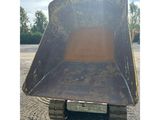 the back end of a bulldozer sitting on gravel in a parking lot