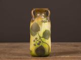 un vase jaune orné de feuilles vertes, posé sur une table