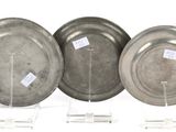three silver plates with labels on them sitting on a stand