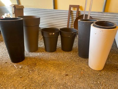 Plusieurs jardinières noires et blanches sont alignées au sol