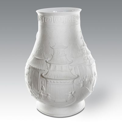 un vase blanc posé sur une table, sur fond gris