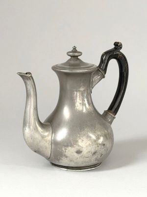 une vieille théière en argent posée sur une table blanche