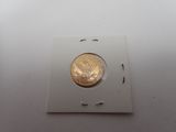 une pièce d'or dans une boîte blanche posée sur une surface blanche