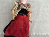 a small doll with a red dress and a black hat