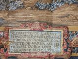 a plaque on the wall of a building with flowers and vines on it