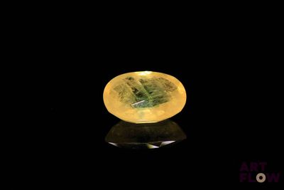 a close up of a yellow sapphire stone on a black surface
