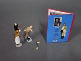two figurines of people standing next to a book