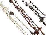 three rosary necklaces with crosses and beads on a white background