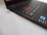 a black laptop with a red keyboard on a white table