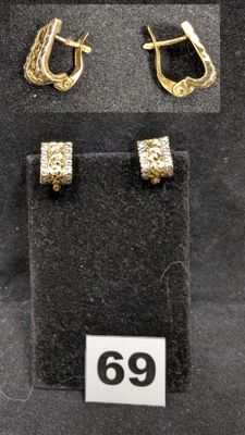 Deux paires de boucles d'oreilles en or sont exposées dans une vitrine.