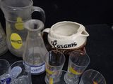 many glasses and jugs sitting on a table next to each other