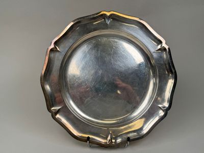 an antique silver plate on a stand on a gray surface