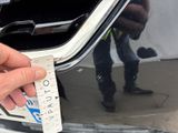 a person holding a ticket that is attached to the front of a car