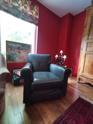 un salon aux murs rouges avec un fauteuil en cuir noir