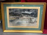 tableau représentant un paysage, dans un cadre doré, posé sur une table