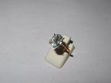 a close up of a ring with a blue stone on a white surface