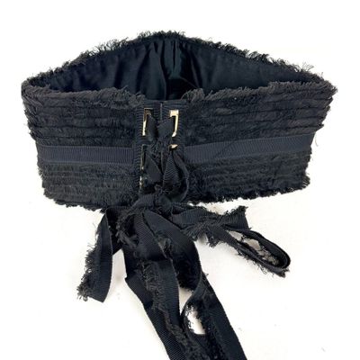 un corset noir muni d'une fermeture éclair, posé sur un fond blanc