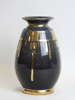 a black and gold vase sitting on a white surface