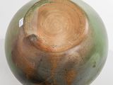 a green and brown vase sitting on a white table