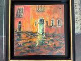 someone holding up a painting of a street scene with buildings in the background
