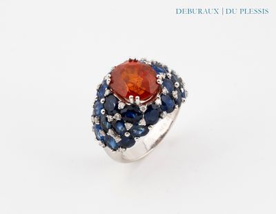 un gros plan d'une bague ornée d'une pierre orange entourée de saphirs bleus