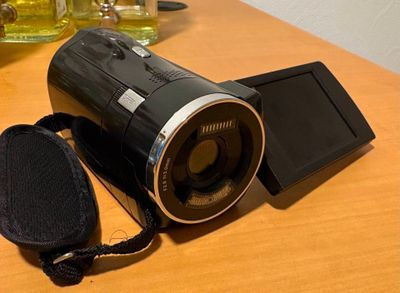 un appareil photo noir posé sur une table, à côté d'un téléphone portable