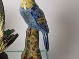 two figurines of birds sitting on a glass table
