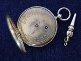 a silver pocket watch with a chain on a blue surface