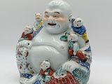 a figurine of a smiling buddha sitting on a pillow