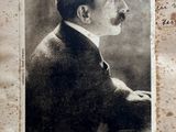 an old photograph of a man in a suit and tie sitting in front of a piece of paper