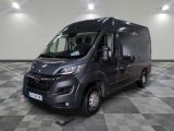 La camionnette grise est garée dans une grande pièce au sol à carreaux.